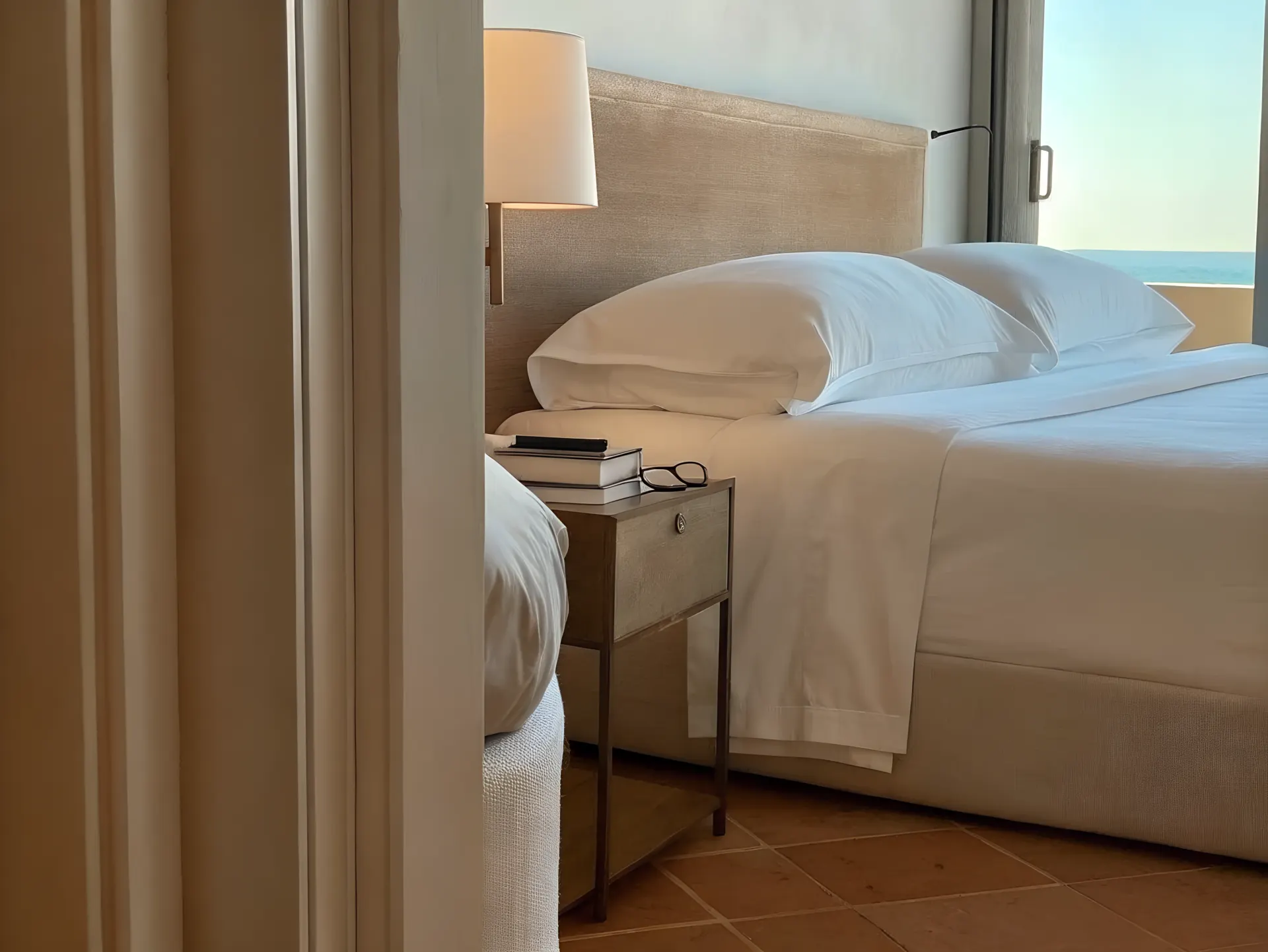 A hotel bedroom with sea view and bedside reading